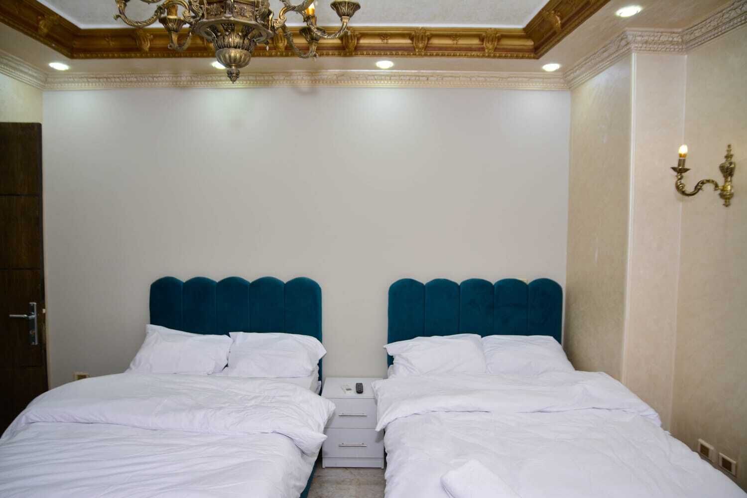 A double bed with a teal headboard in a hotel room.