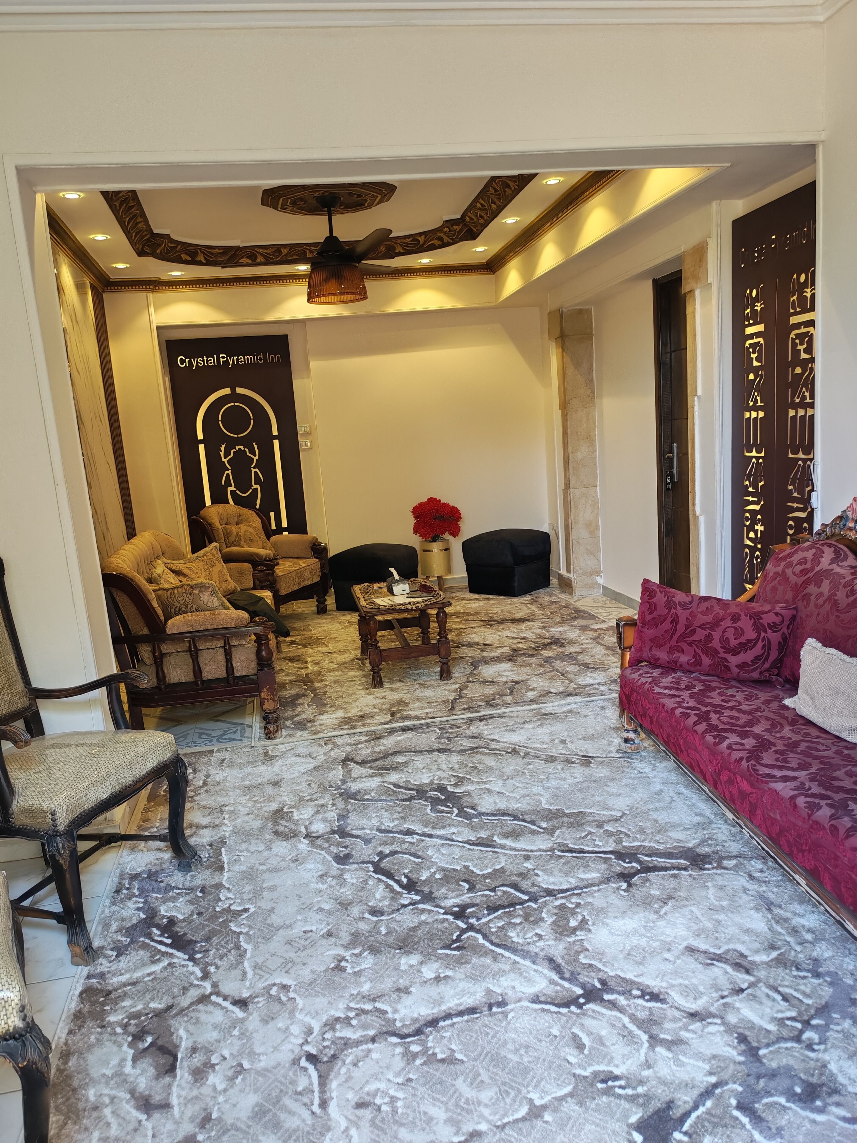 A spacious living area with a marble floor, a red sofa, and a wooden coffee table.