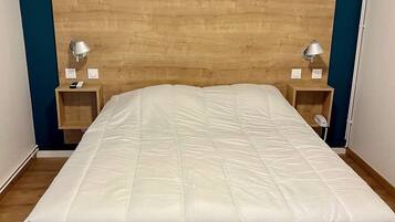 A bed with a wooden headboard, two bedside tables with lamps, and a blue accent wall.