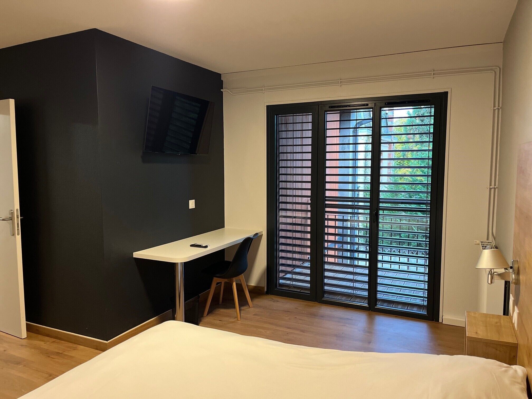 A bedroom with a bed, a desk, and a chair.