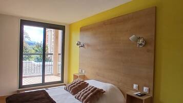 A bedroom with a large bed, a wooden headboard, and a view through a sliding glass door.