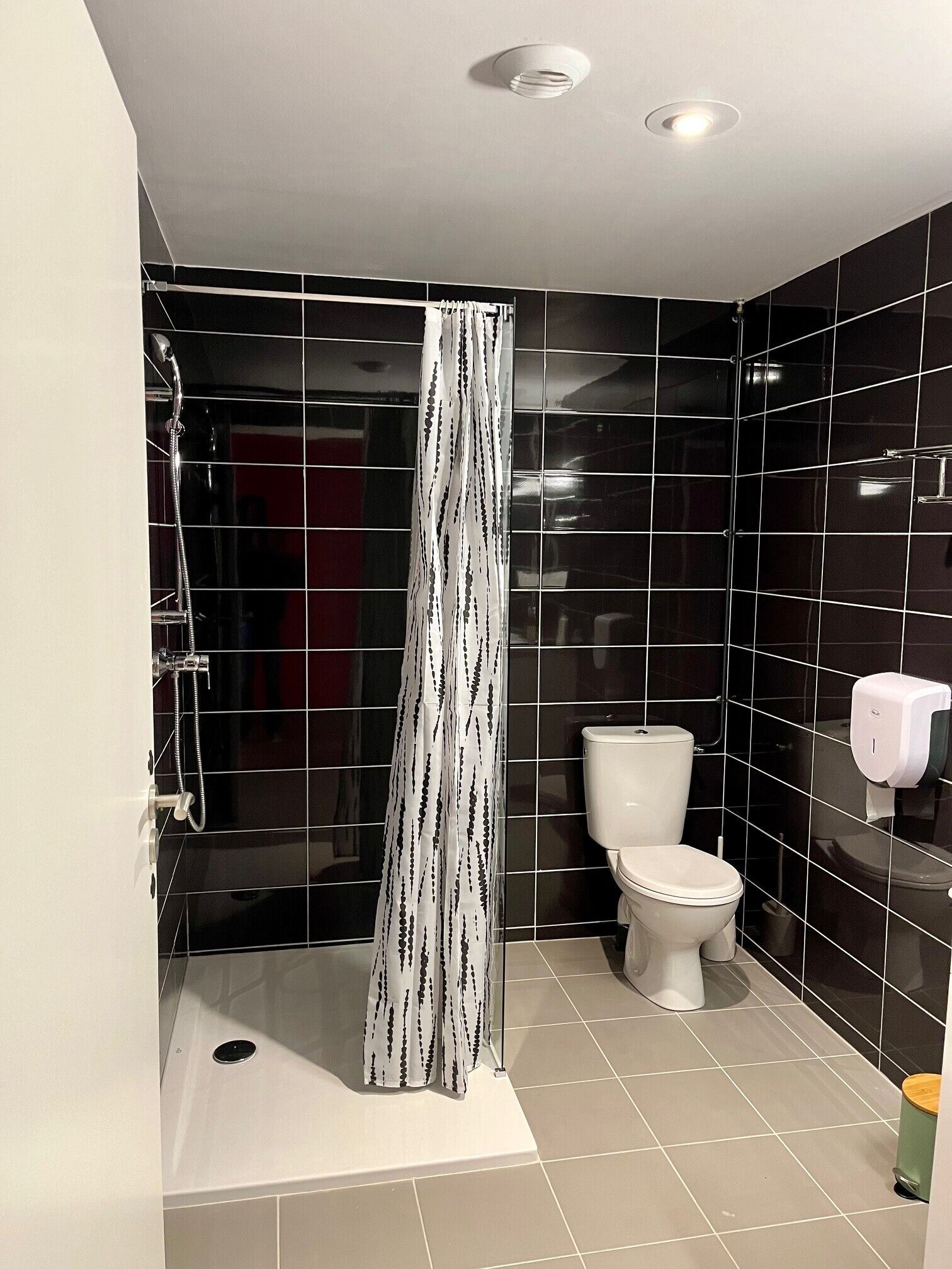 Un baño con ducha, inodoro y secamanos.