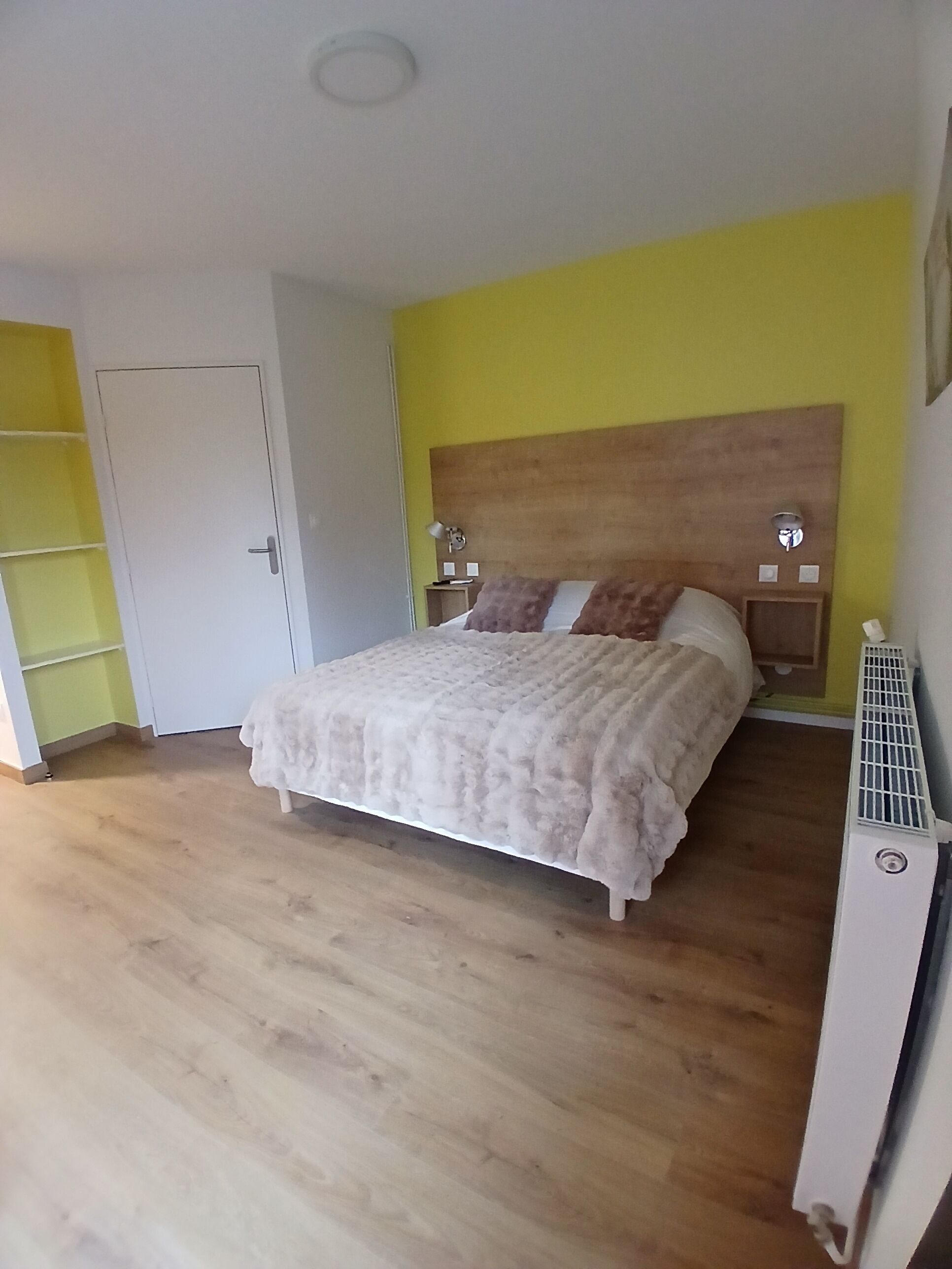 A bedroom with a bed, a bedside table, a nightstand, a heater, and a wardrobe.