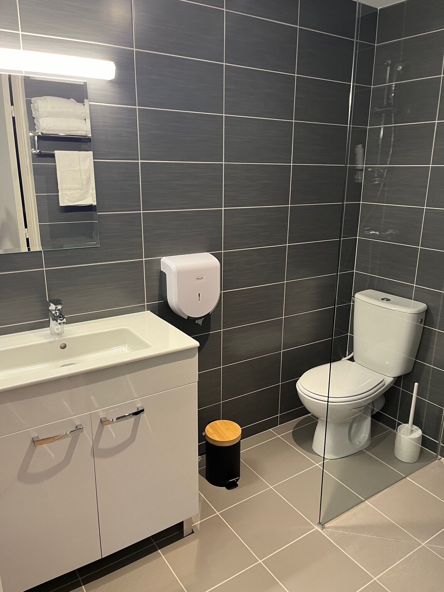 A modern bathroom with a white sink, a toilet, and a hand dryer.