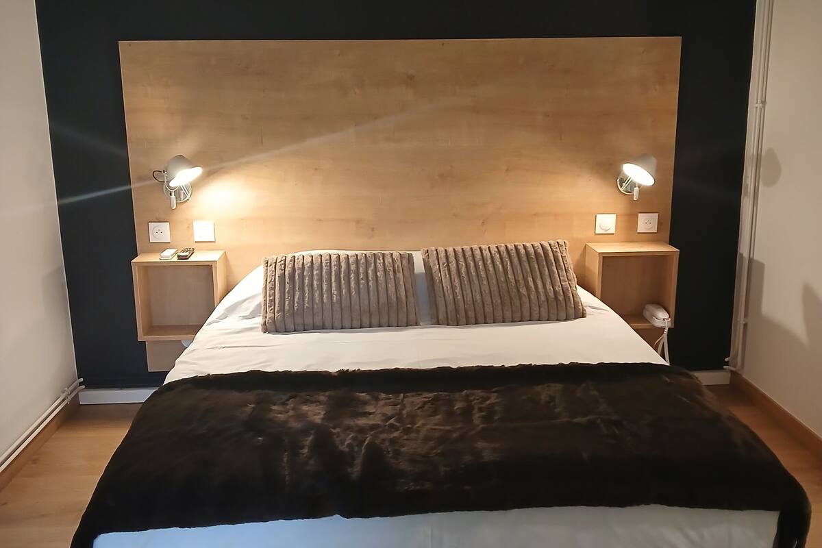 Ein modernes Schlafzimmer mit einem großen Bett, zwei Nachttischen mit Lampen und einem Holz-Kopfteil.