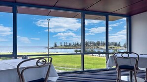 A room with large windows offering a view of the sea and a golf course.