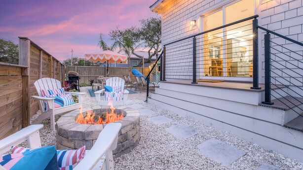 Un patio trasero con un brasero, mobiliario exterior y una zona cubierta.