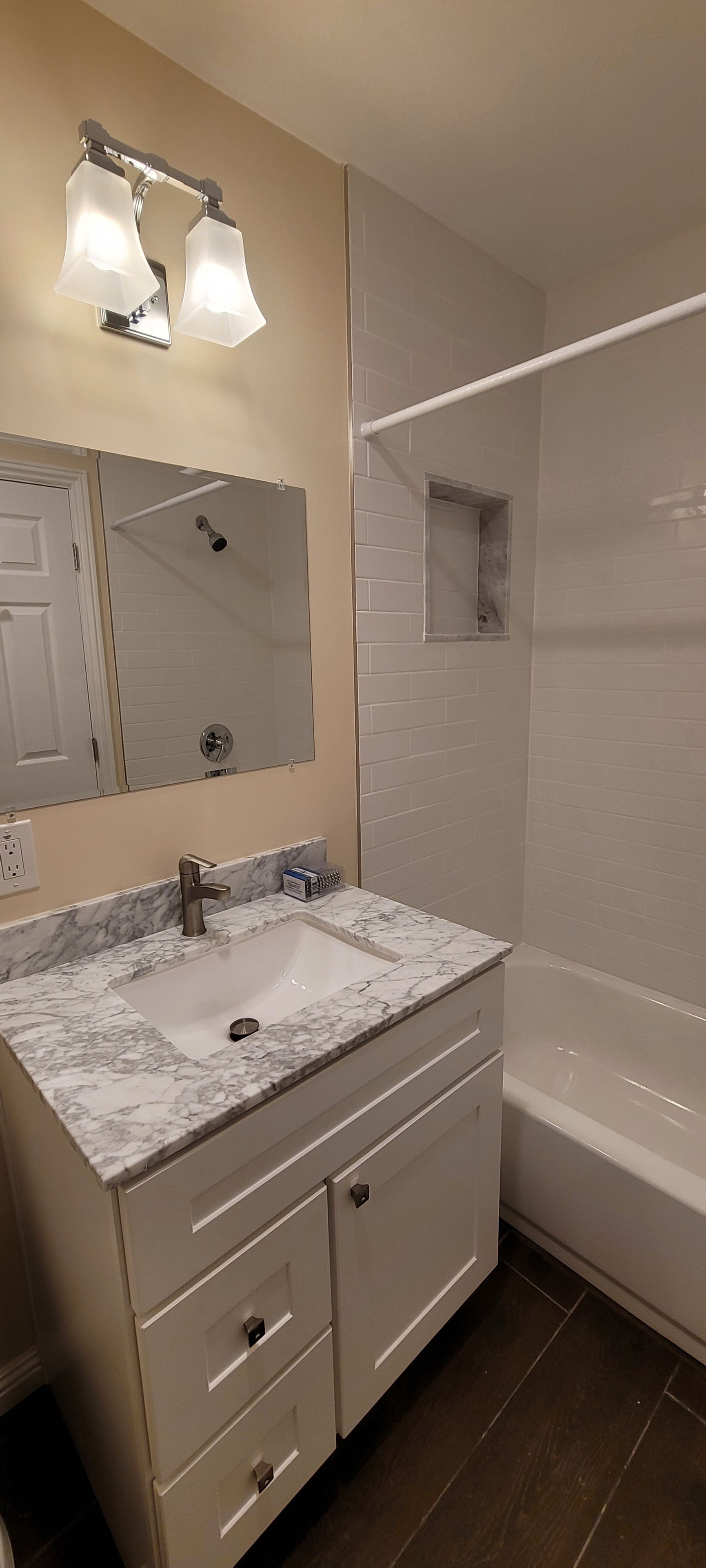 Un baño con lavamanos de mármol, espejo, ducha y bañera.