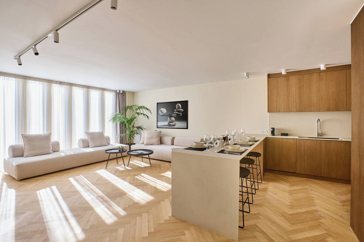 A modern living space with a large sofa, a dining area, and a kitchen.