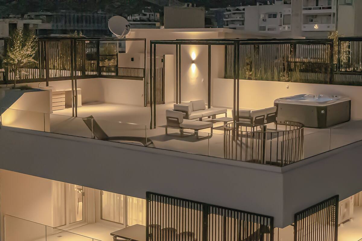 A modern rooftop terrace with a sofa, chairs, and a hot tub.