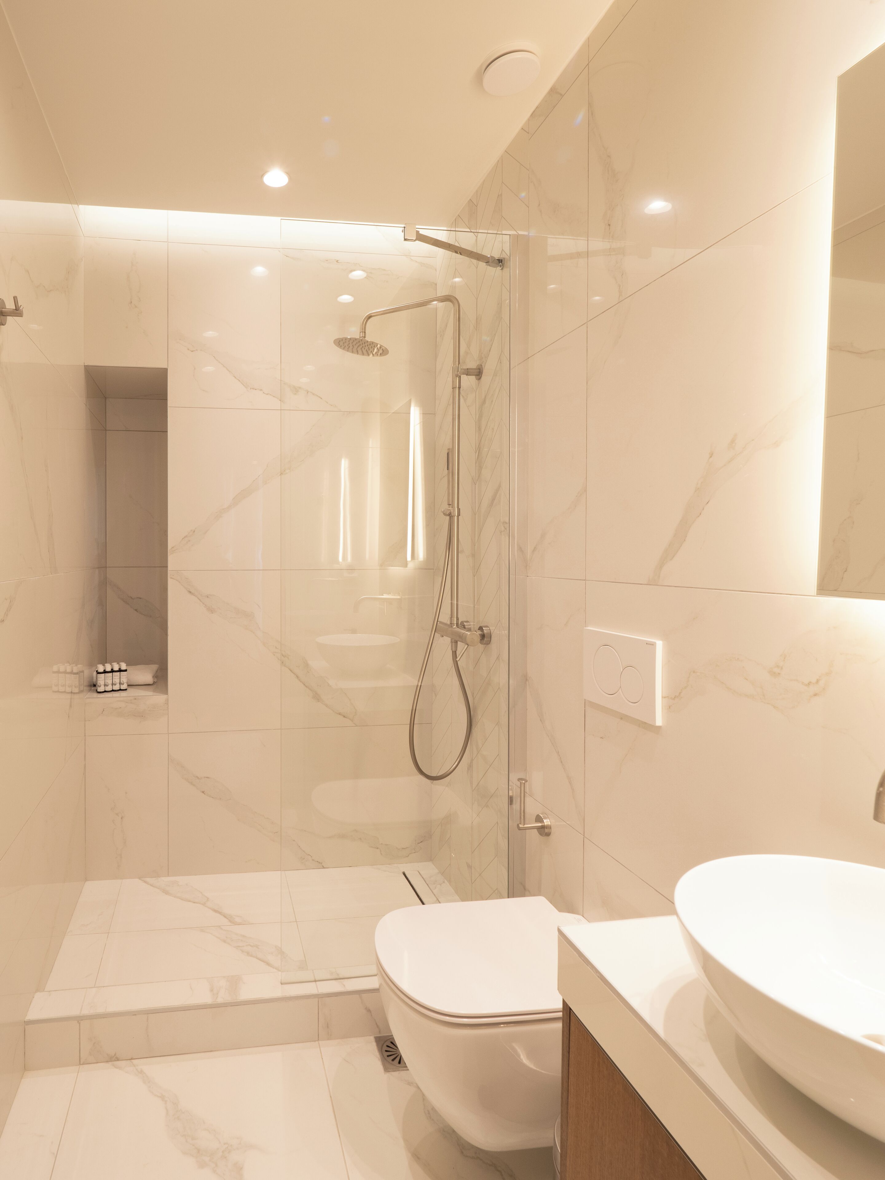 Ein modernes Badezimmer mit einer gläsernen Duschkabine, einer weißen Toilette und einem Waschtisch.