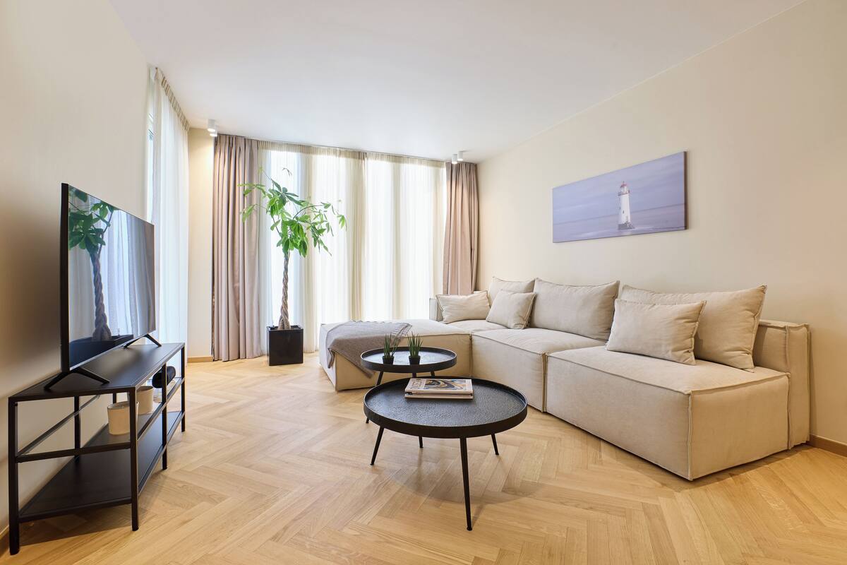 A modern living room with a sofa, a coffee table, a TV stand, and a potted plant.