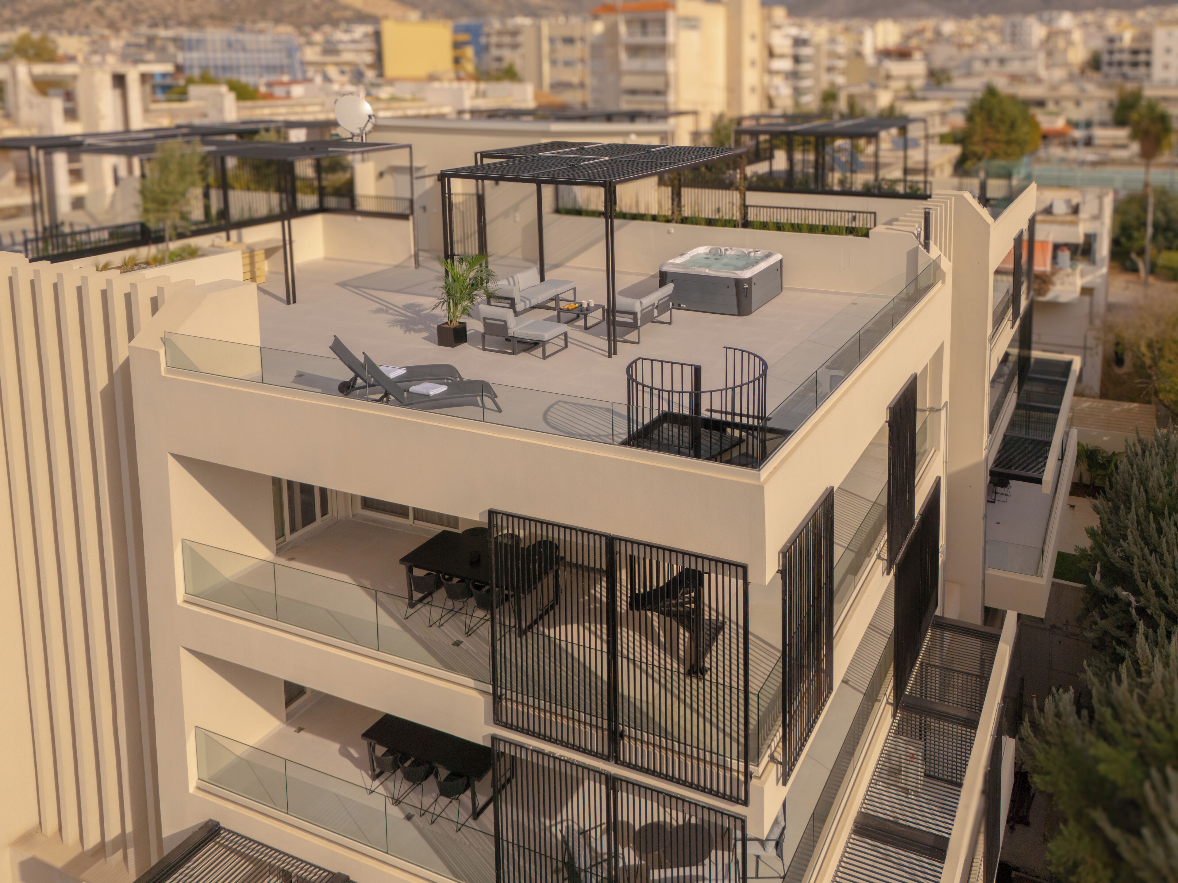 Un edificio moderno con varios balcones, zonas de estar al aire libre y una azotea con paneles solares.