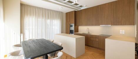 A modern kitchen with wooden cabinets, a central island, and a dining area with a table and chairs.