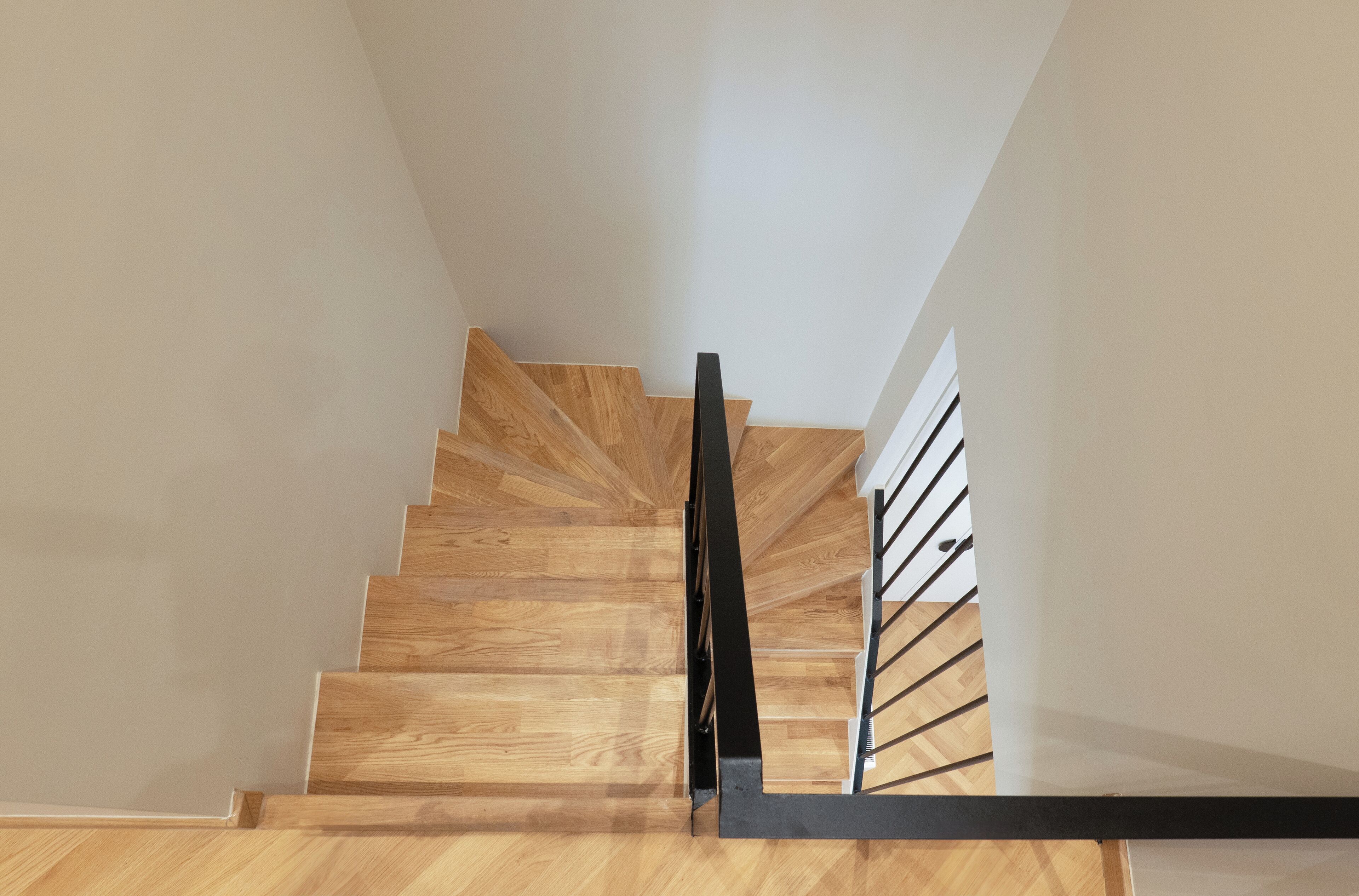 Un escalier en bois avec des rampes noires menant à un palier.