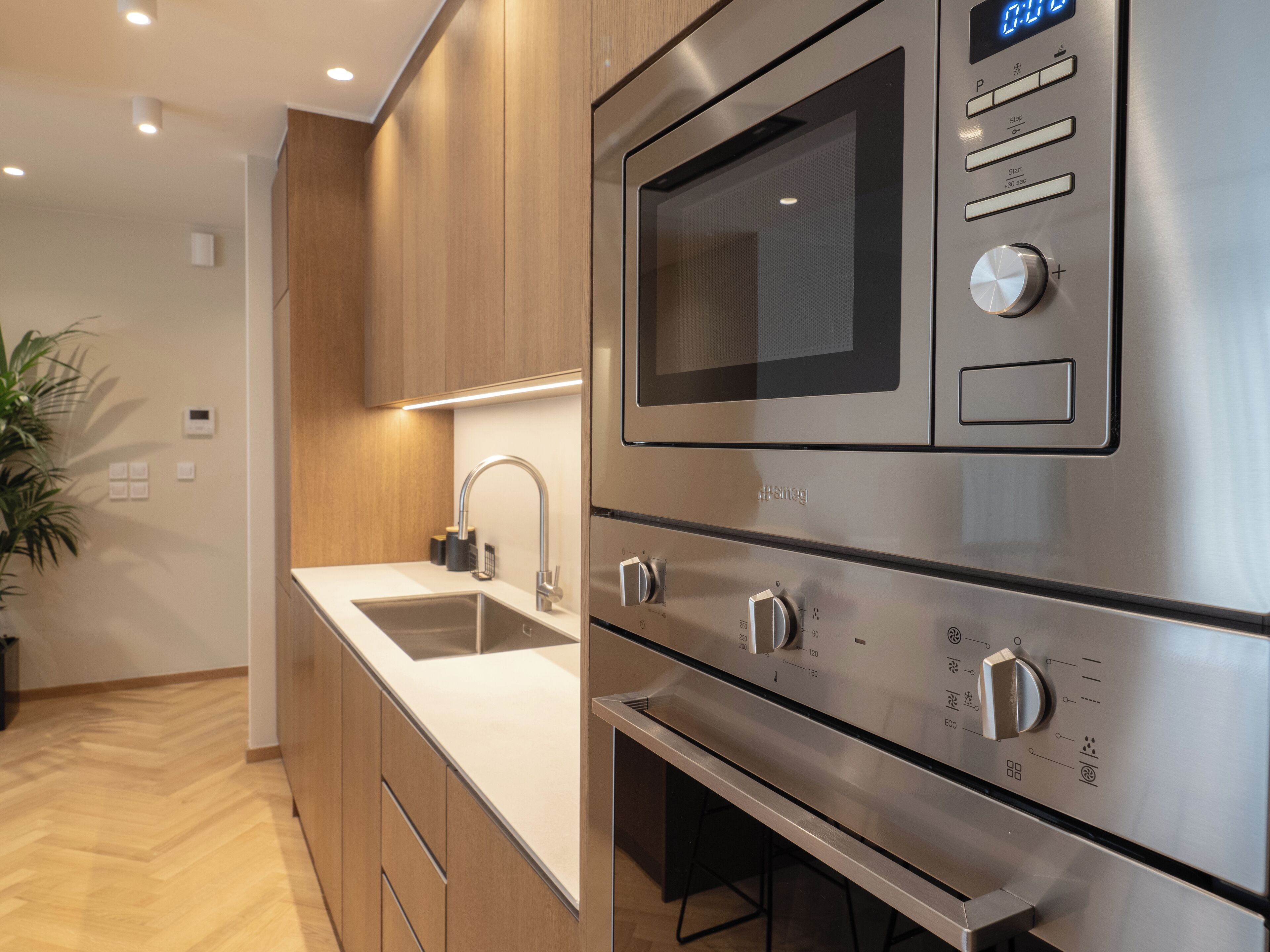 A modern kitchen with stainless steel appliances, a double sink, and wooden cabinets.