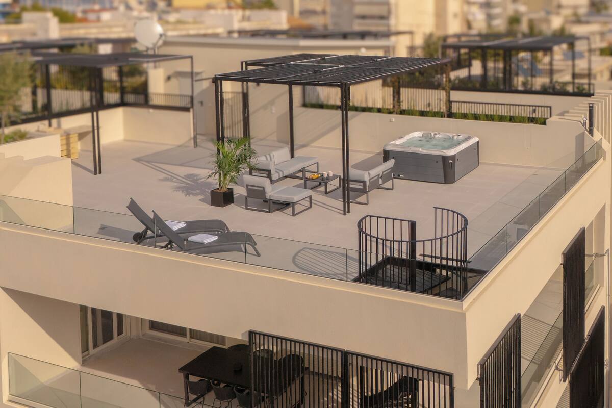 A rooftop terrace with outdoor seating, a hot tub, and a potted plant.