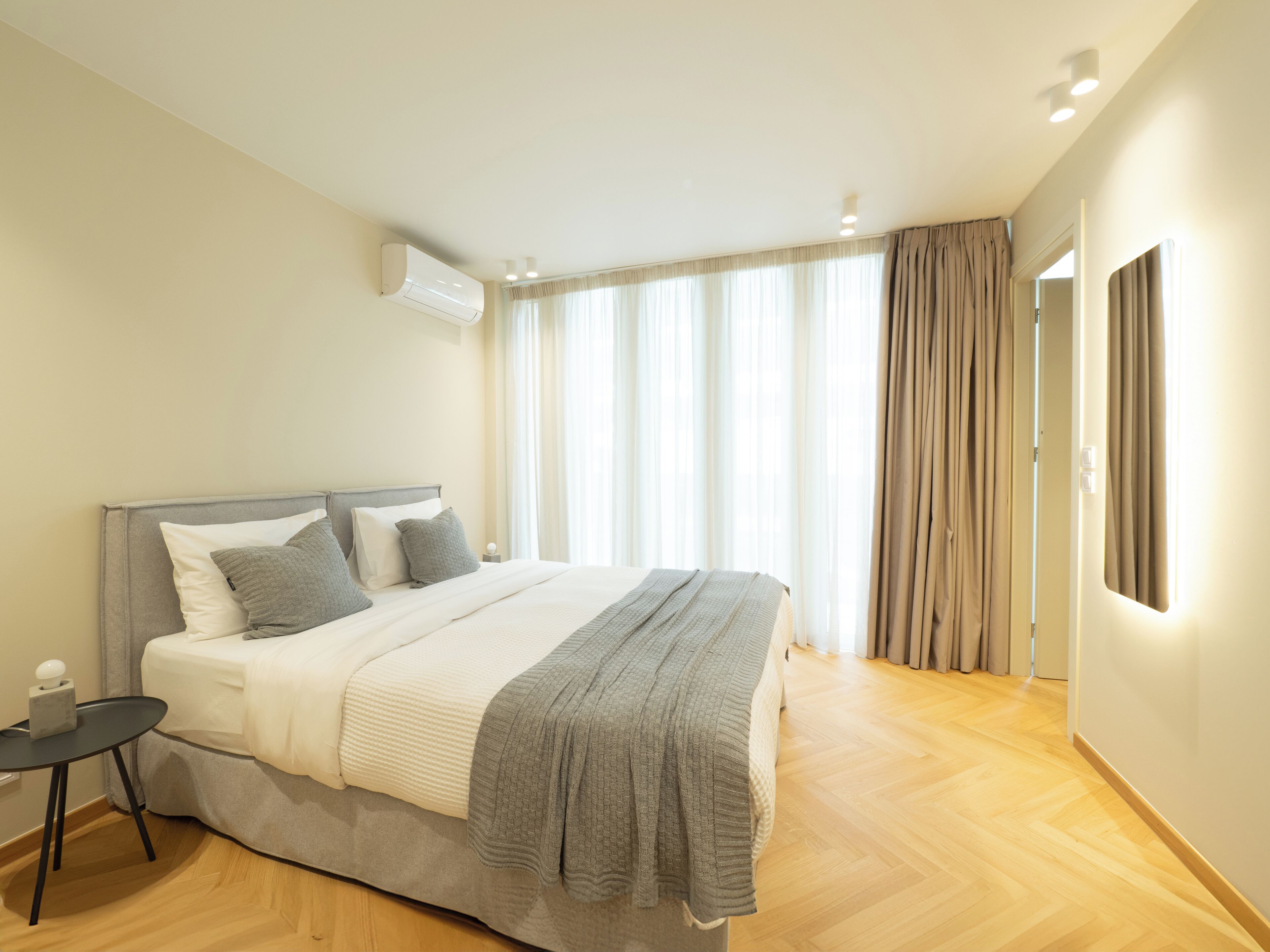A modern bedroom with a large bed, a bedside table, and a window with curtains.