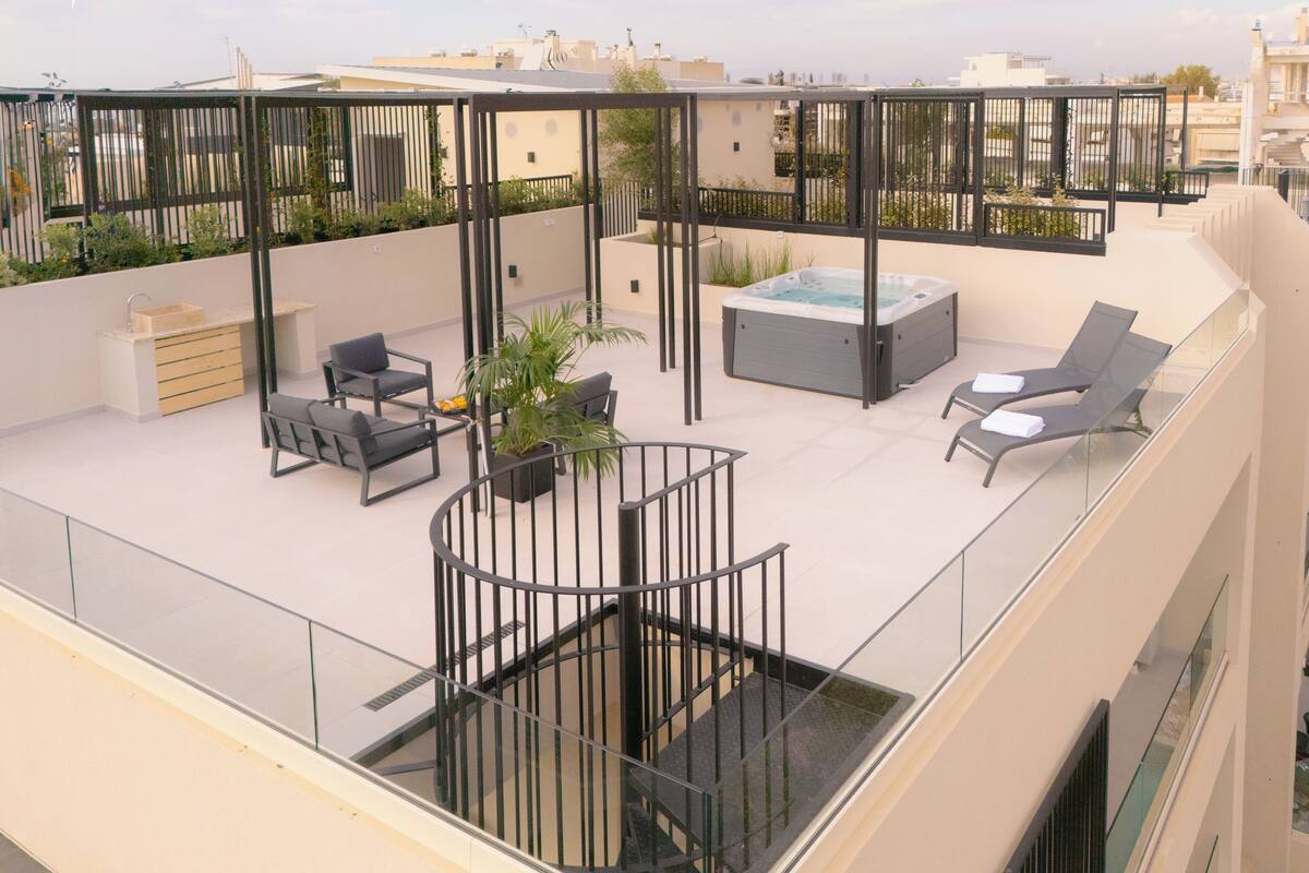 A rooftop terrace with a hot tub, seating area, and potted plants.