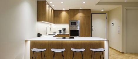 A modern kitchen with a central island, bar stools, and built-in appliances.