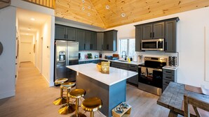 A modern kitchen with a central island, stainless steel appliances, and a wooden ceiling. - The Perfect Modern Killington Getaway
Hot tub-Sauna-Movie Room-Speakeasy-VIEWS! (Killington)