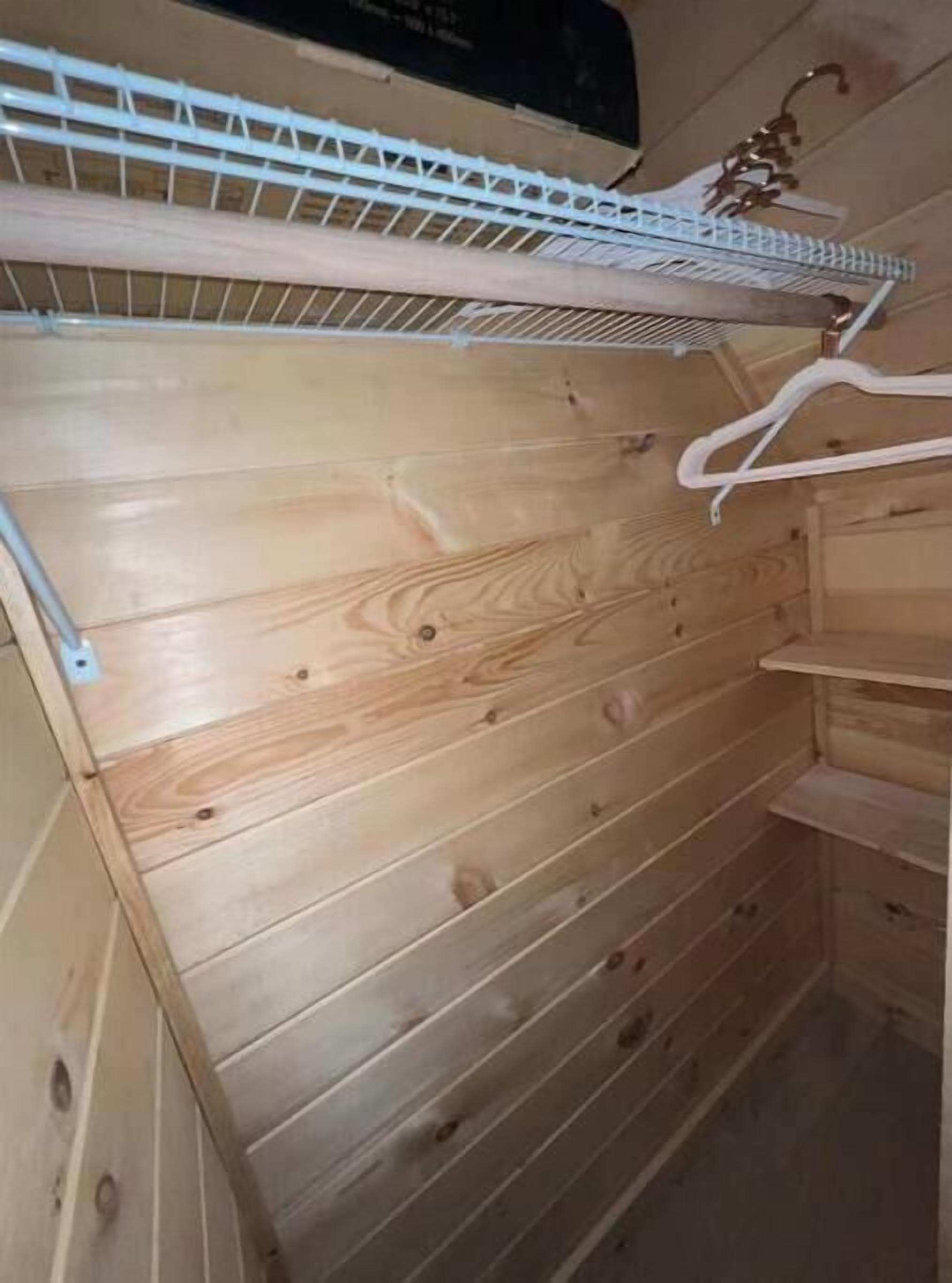 A wooden wall with a white metal shelf and a white hanger.