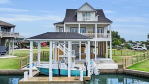Una casa de dos pisos con un muelle y un bote.