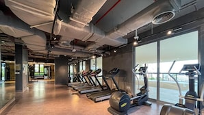 Une salle de sport équipée de tapis de course, de vélos elliptiques et de matériel de musculation.