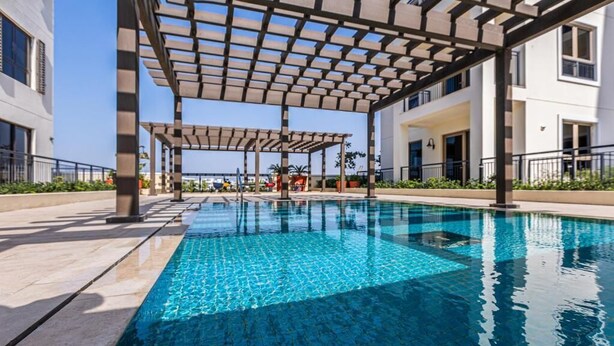 Une piscine surmontée d’une pergola, entourée d’un espace aménagé avec vue sur la mer.