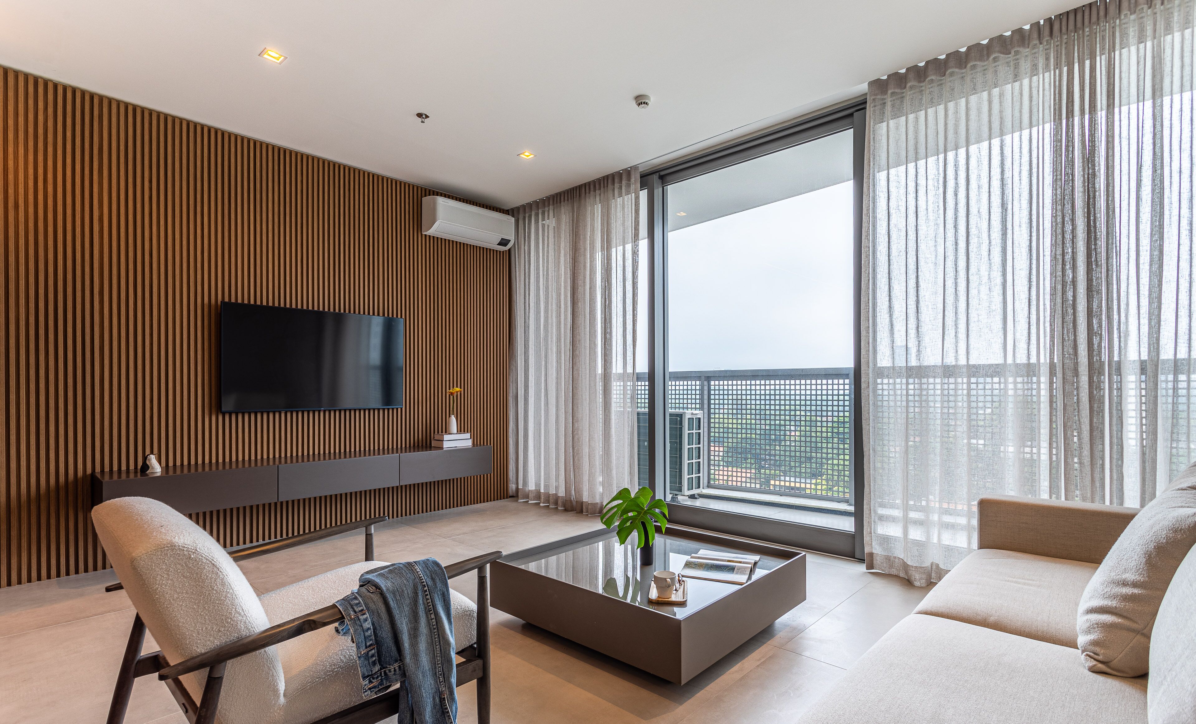 A modern living room with a flat-screen TV, a coffee table, and a sofa.