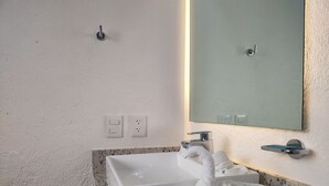 A bathroom with a white sink, a mirror, and a towel rack. - Departamento Caracol (Puerto Vallarta)