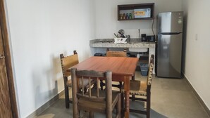 A compact kitchen with a wooden dining table and chairs, a built-in microwave, and a stainless steel refrigerator. - Departamento Caracol (Puerto Vallarta)