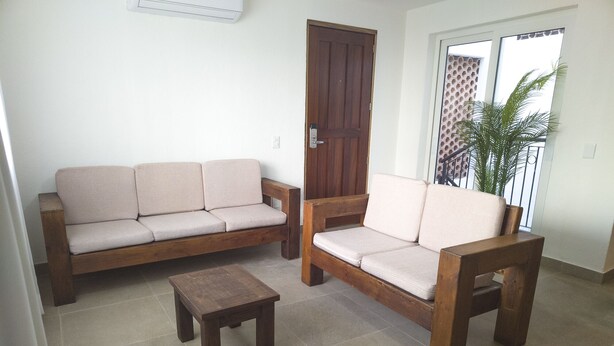 A living room with a sofa set, a coffee table, and a door. - Departamento Caracol (Puerto Vallarta)