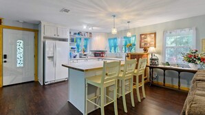 A kitchen with a central island, white cabinets, and a dining area with chairs. - Family Friendly Cottage - Game Room+firepit+smores (Broken Bow)