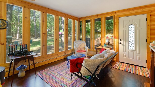 A cozy cabin interior with large windows, a wooden ceiling, and a comfortable seating area. - Family Friendly Cottage - Game Room+firepit+smores (Broken Bow)