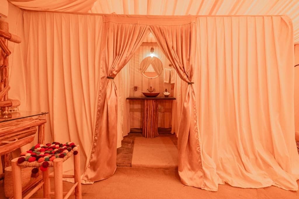 Une pièce avec un banc en bois, un miroir et un lavabo.