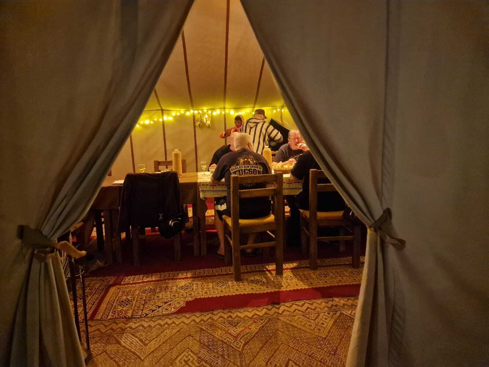 A tented dining area with a table, chairs, and string lights.