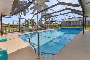 A covered swimming pool with lounge chairs and a view of palm trees. - Pool Time and Fun Times at Mermaid Dream (Cape Coral)