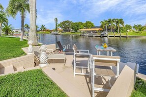 A waterfront patio with outdoor furniture, a small table, and a chair. - Pool Time and Fun Times at Mermaid Dream (Cape Coral)