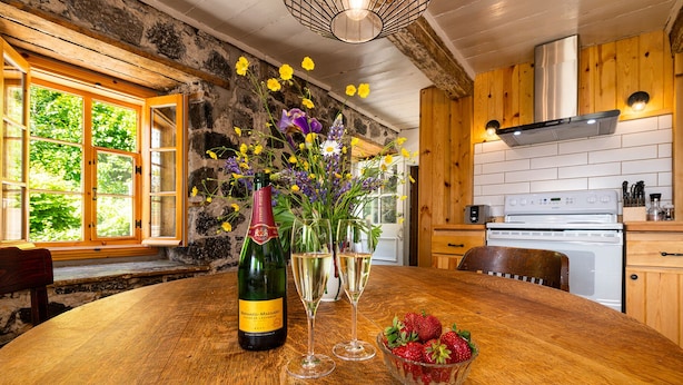 Een houten eettafel met champagne, glazen en een schaal aardbeien.