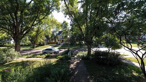 Una calle residencial con casas, un automóvil estacionado y abundante vegetación.