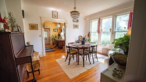 Comedor con una mesa y sillas de madera, un candelabro y vistas al exterior a través de amplios ventanales.