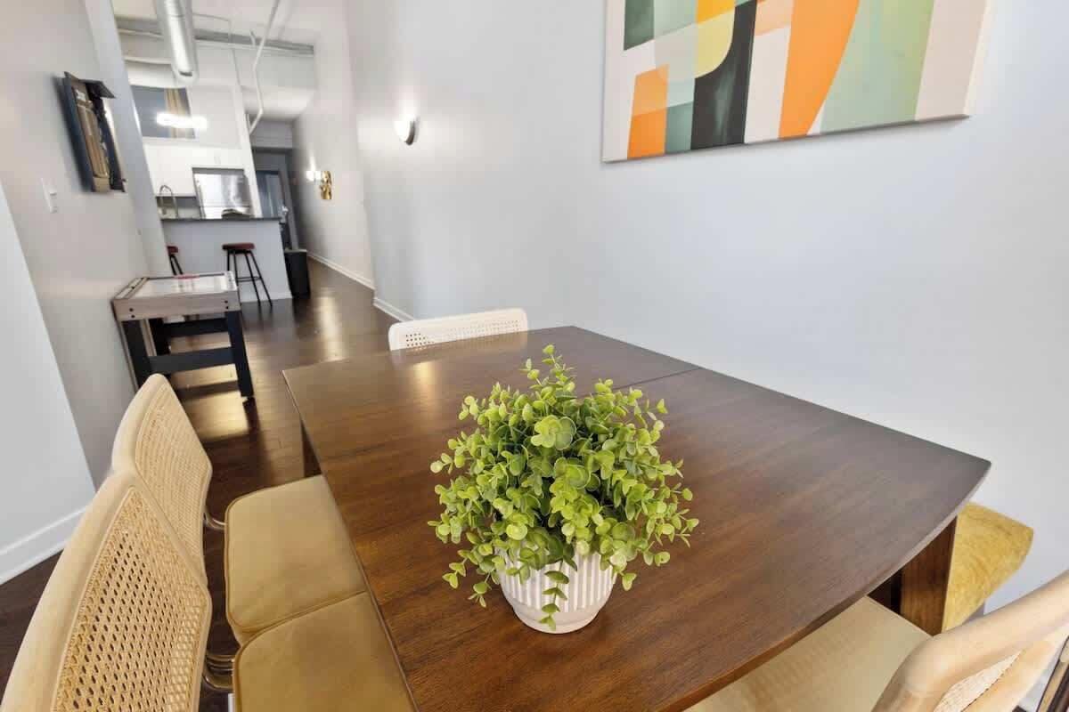 Un comedor con una mesa de madera, sillas color beige y una planta en maceta.