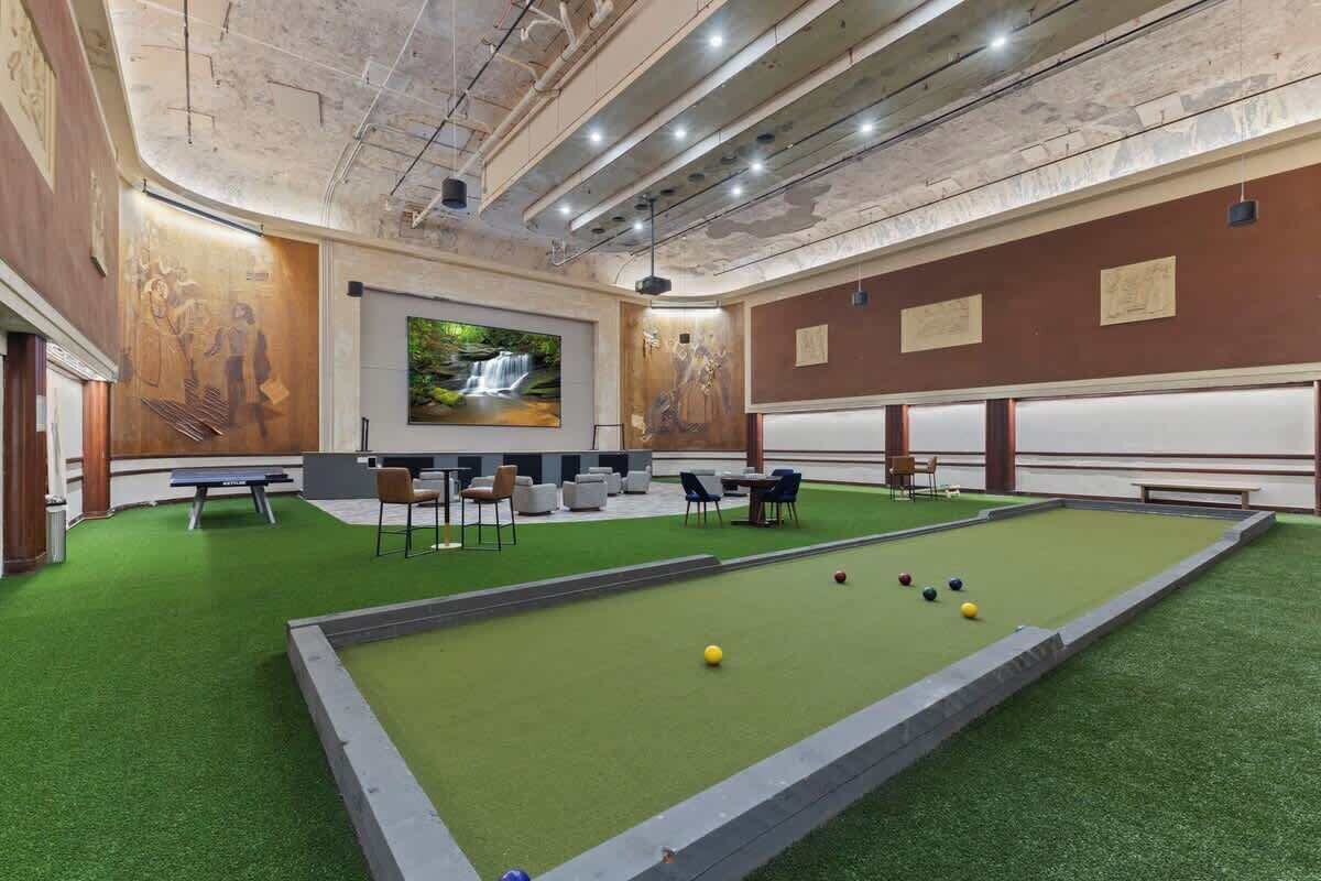 A billiards room with a green felt table, chairs, and a projector screen displaying a waterfall.