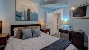 A bedroom with a bed, bedside tables, a dresser, a mirror, and a painting on the wall.