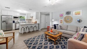 A modern kitchen with white cabinets, stainless steel appliances, and a central island with bar stools.
