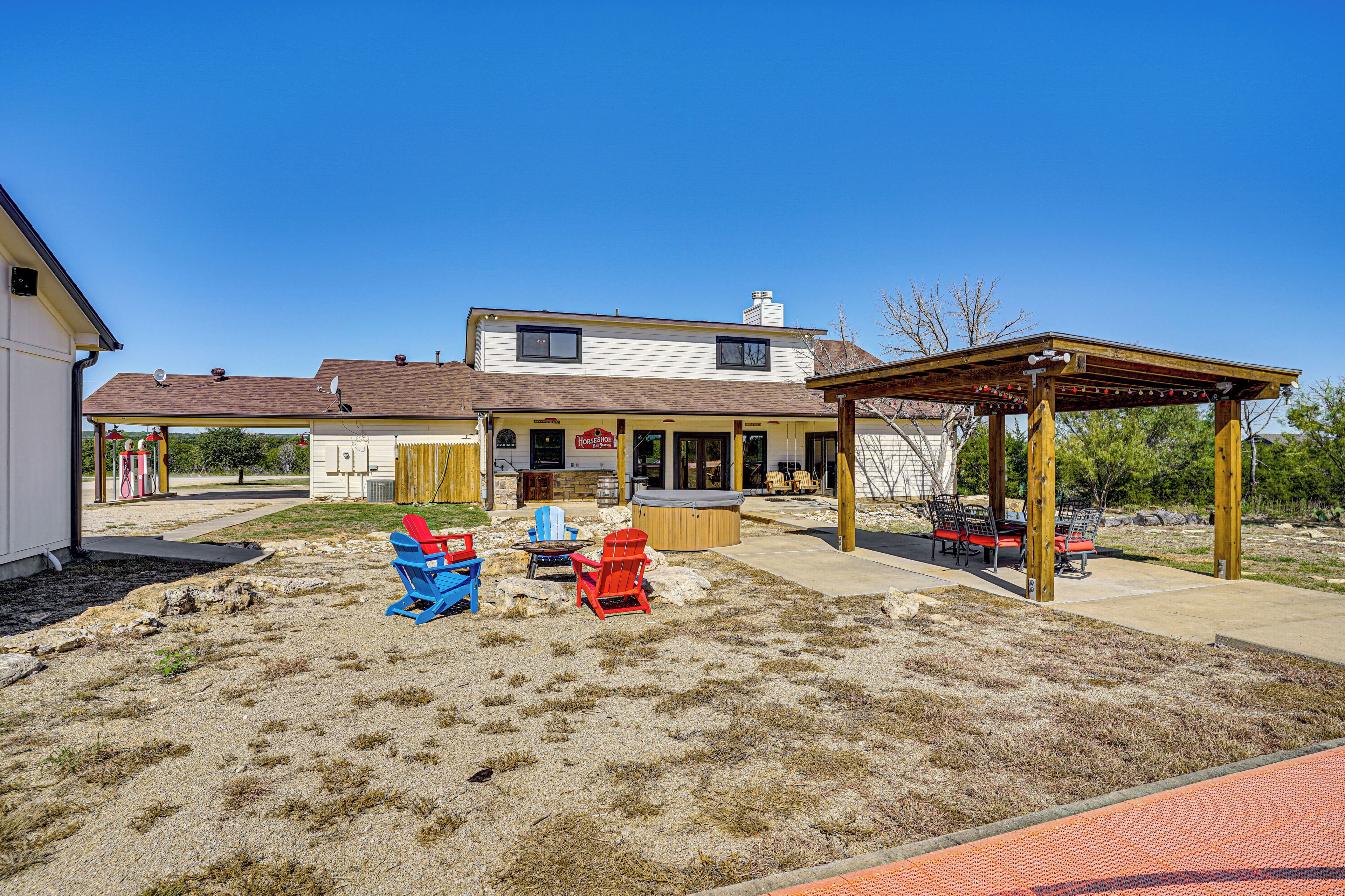 A backyard with a covered patio, outdoor seating, and a hot tub.