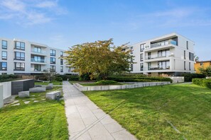 Un immeuble d’appartements moderne doté d’un espace vert central, d’escaliers en béton et offrant une vue sur un ciel dégagé.