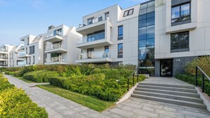 A modern apartment building with multiple balconies, a well-maintained garden, and a clear sky. - Okrzei Residence - Nadmorska Bryza by GA (Sopot)