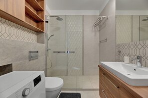 Une salle de bain moderne équipée d’une douche, de toilettes et d’un meuble-lavabo.